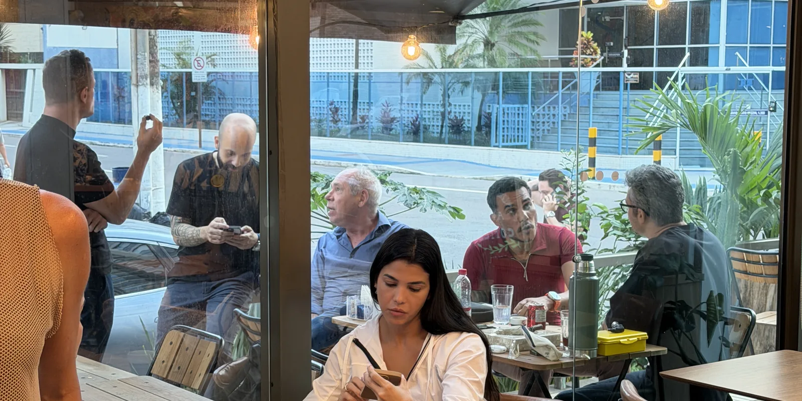 Salão do café com luz natural, mesas de madeira e lâmpadas suspensas