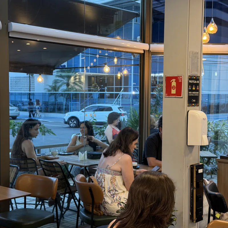 Mesas junto à vitrine envidraçada com vista para a rua